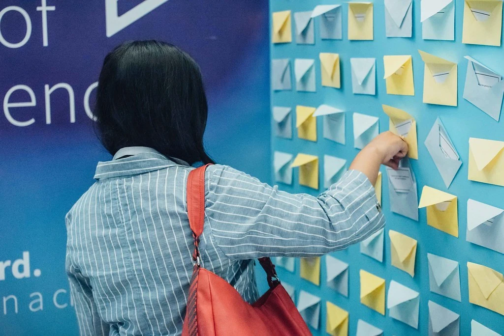 A participant adding a note to an interactive wall at Beyond Resilience.
