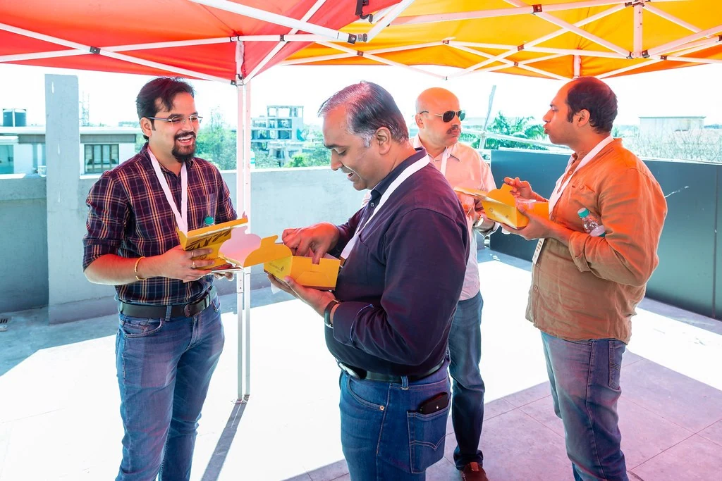 Attendees in conversation beneath a red canopy at Nudge.