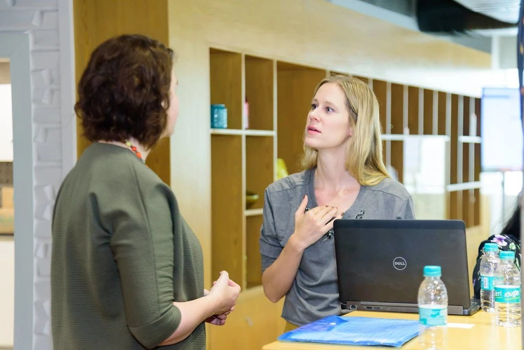 A facilitator in conversation with a participant at Purpose & Progress.