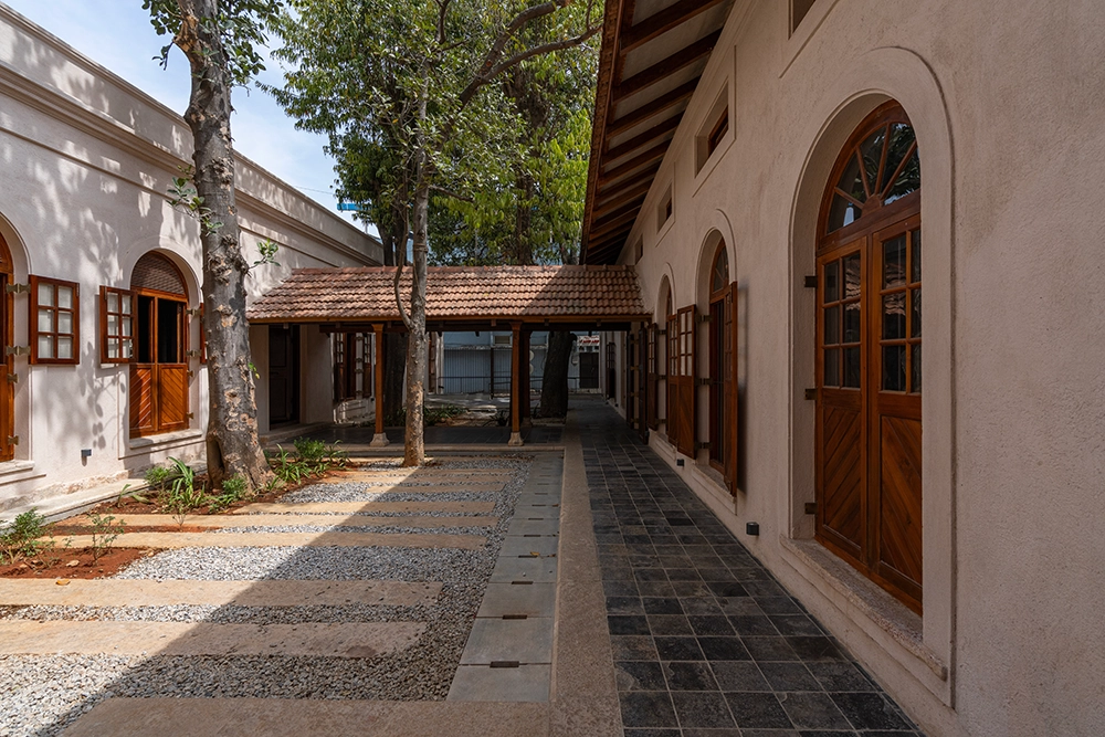 Sabha’s heritage courtyard with a tree and arched wooden doors